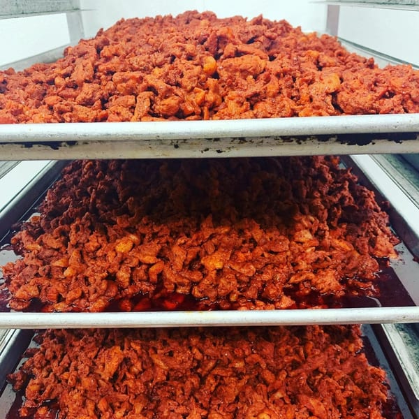 Three trays overflowing with seasoned red al pastor meat, ready for Tacos Al Carbon.